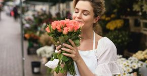 Woman florist with a heap of rose flowers in her little flower shop