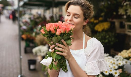 Woman florist with a heap of rose flowers in her little flower shop